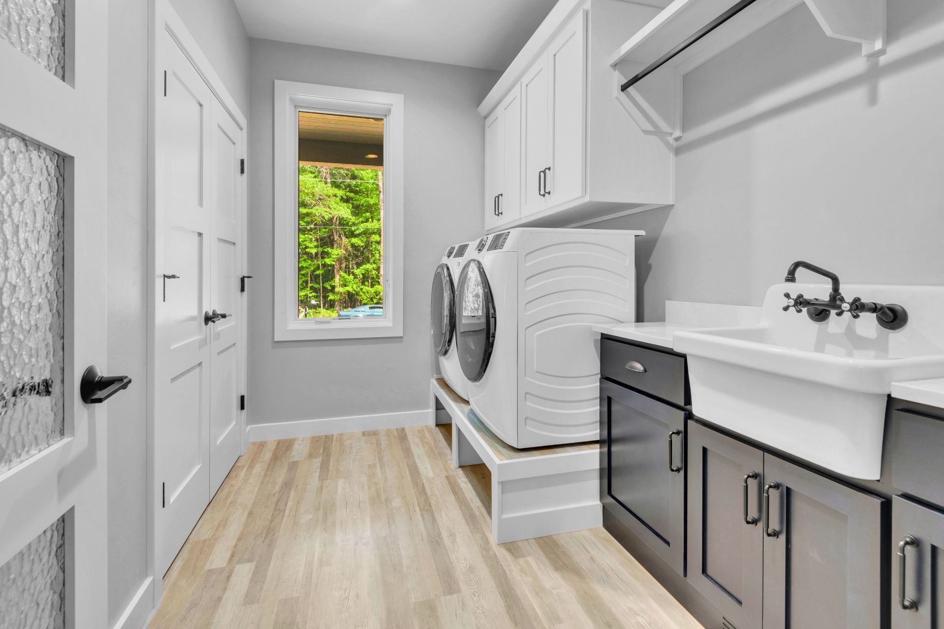 A laundry room with a washer and dryer , sink , cabinets and a window.