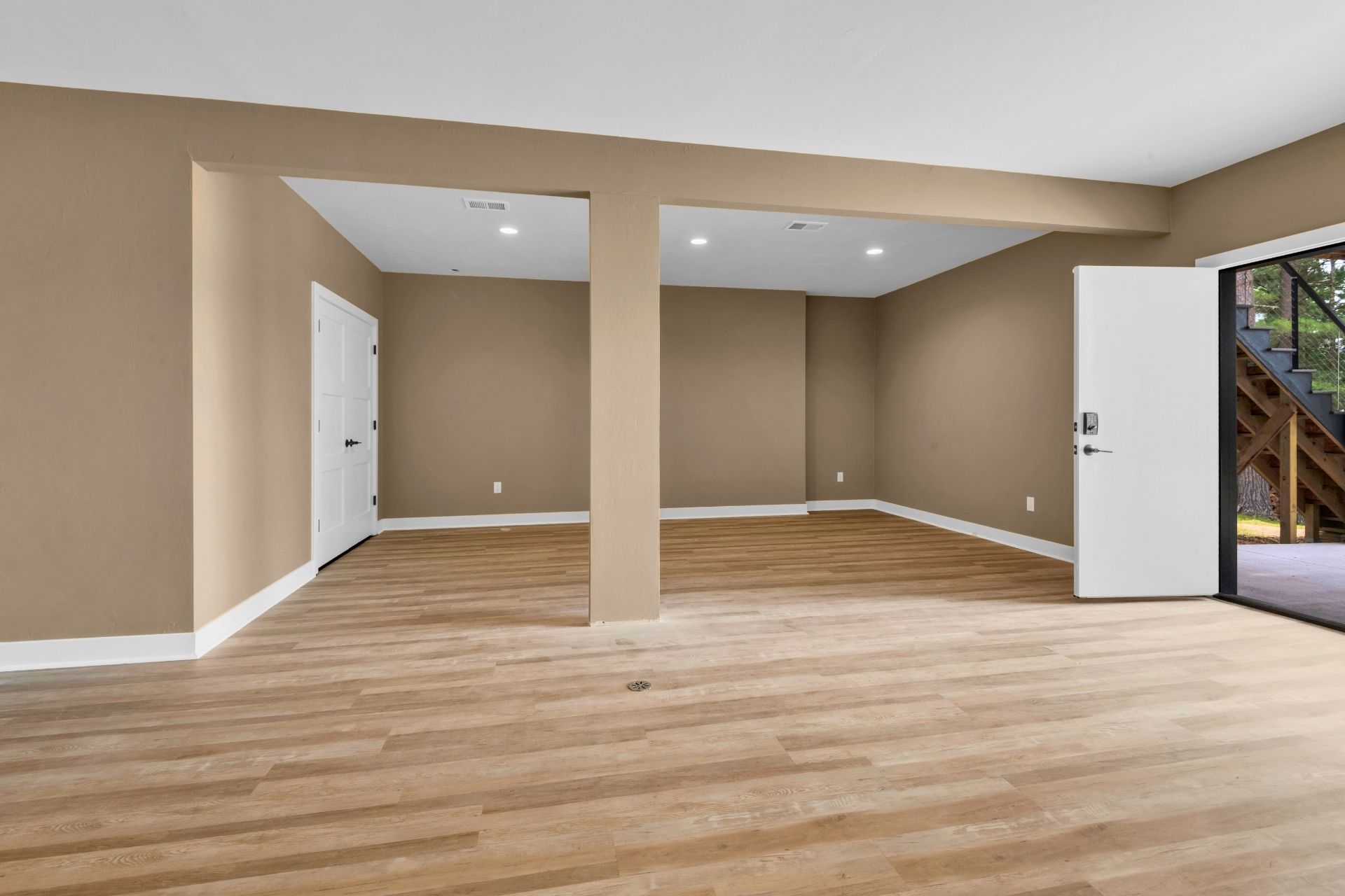 A large empty room with hardwood floors and brown walls.