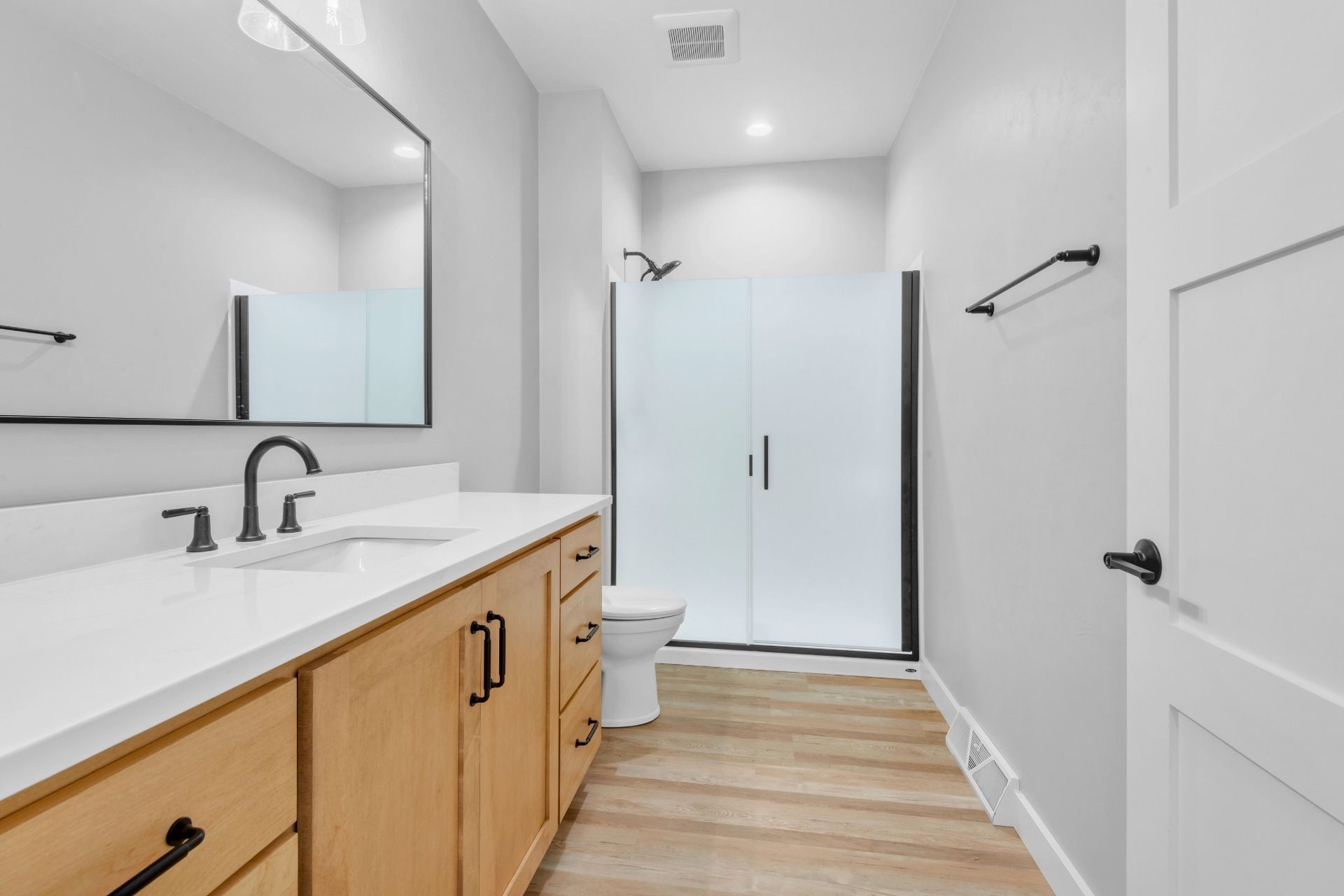 A bathroom with two sinks , a toilet , and a walk in shower.