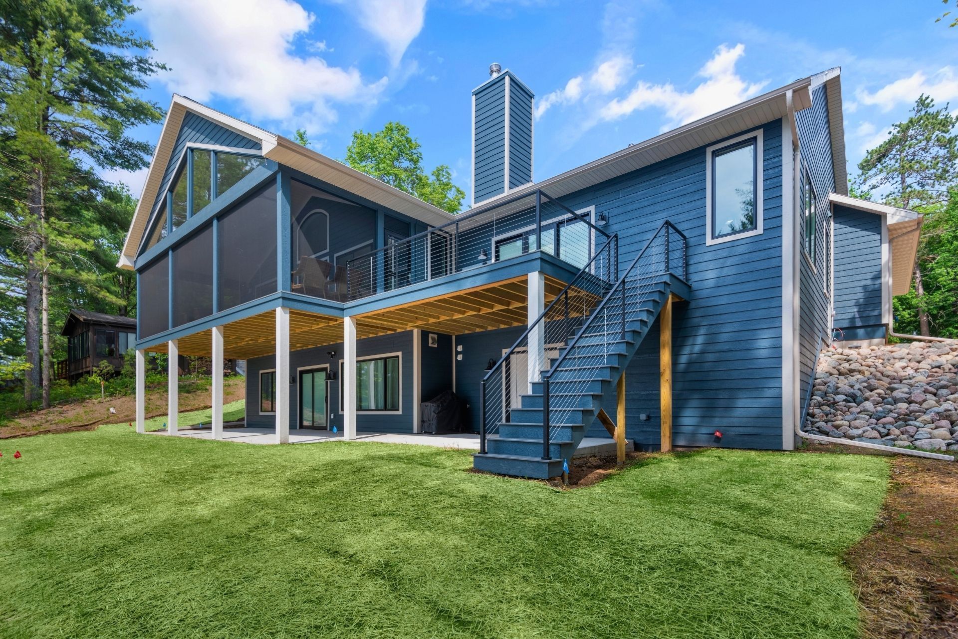 A large blue house with a screened in porch and stairs.