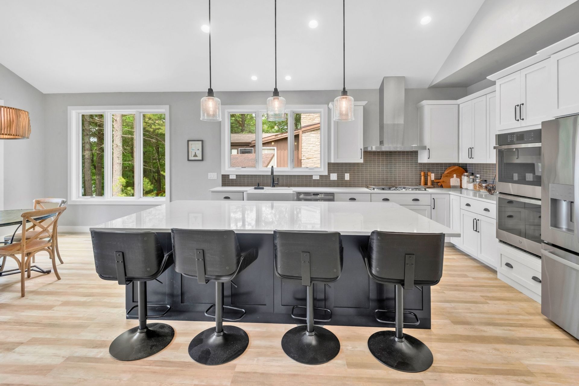A kitchen with white cabinets , stainless steel appliances and a large island.