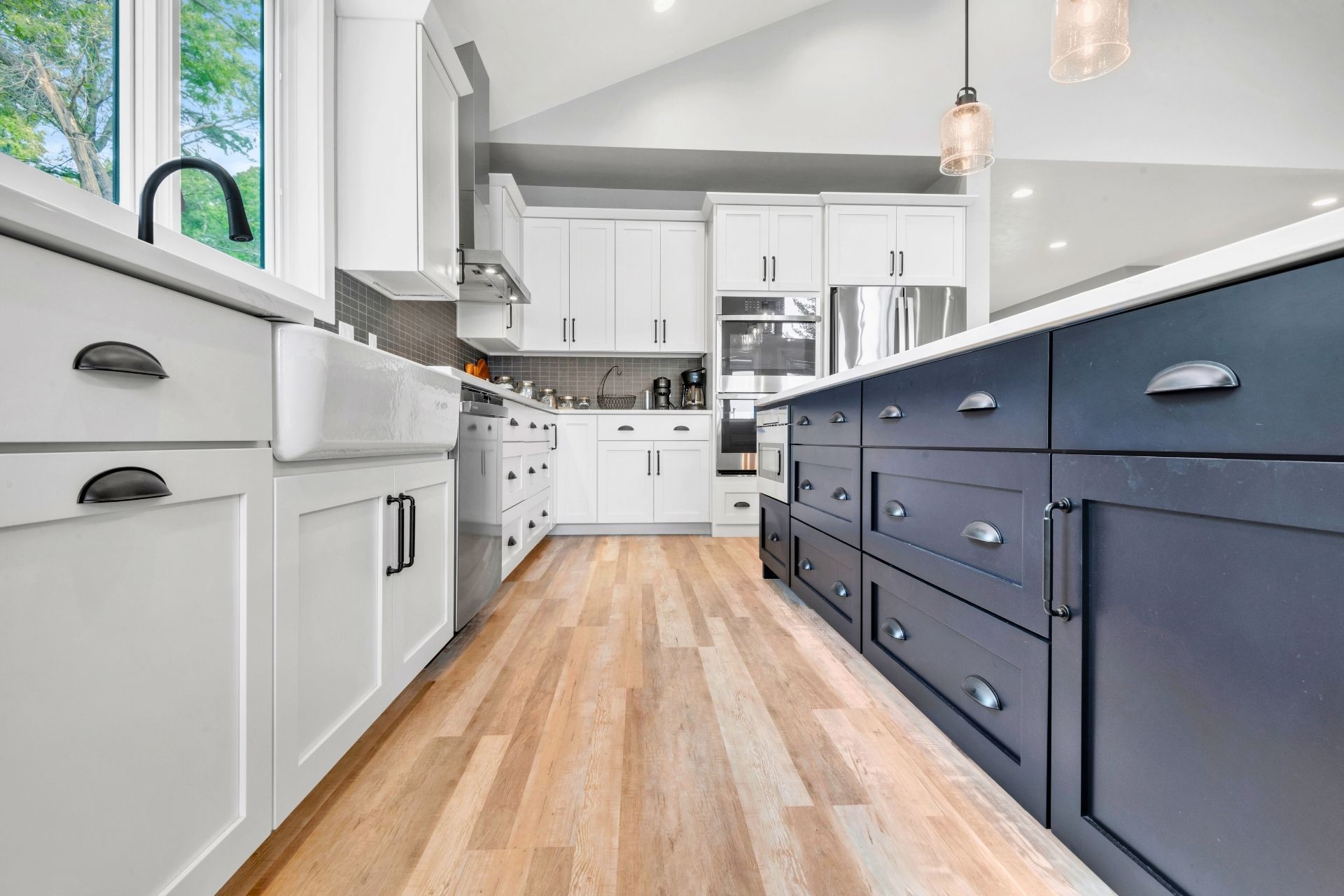A kitchen with white cabinets and blue drawers and a wooden floor.