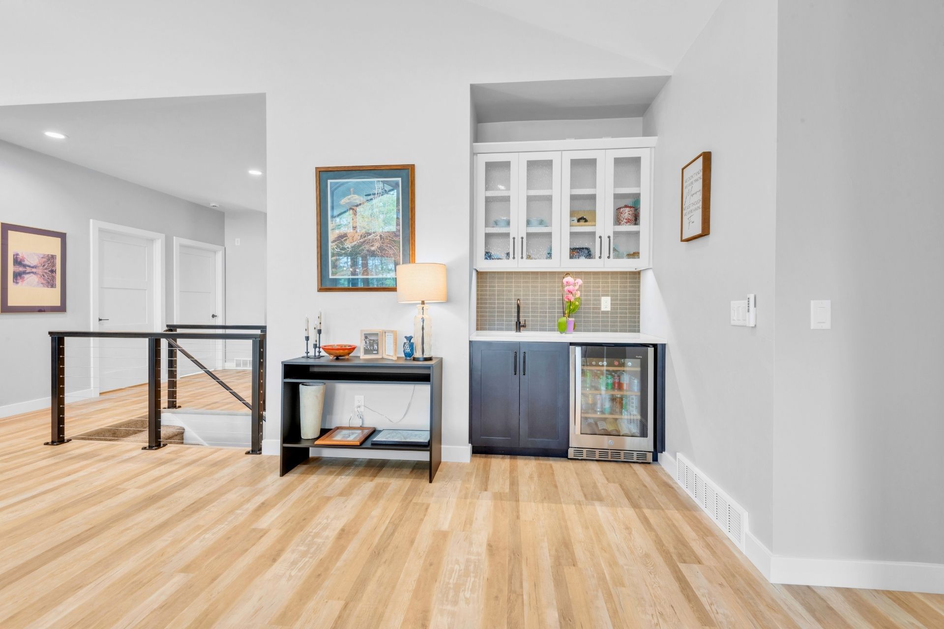 A living room with hardwood floors , a table and a refrigerator.