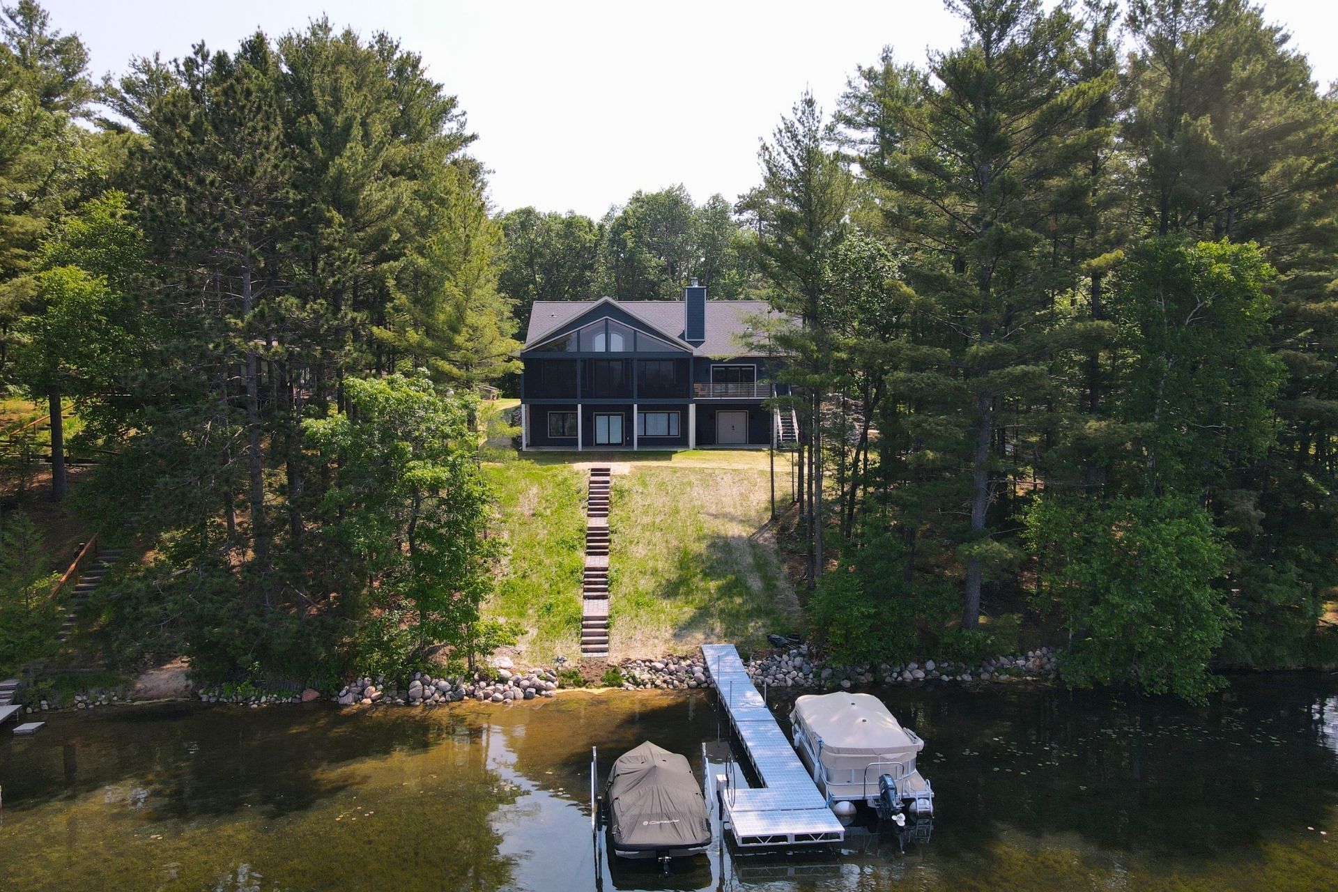 An aerial view of a house on a lake surrounded by trees