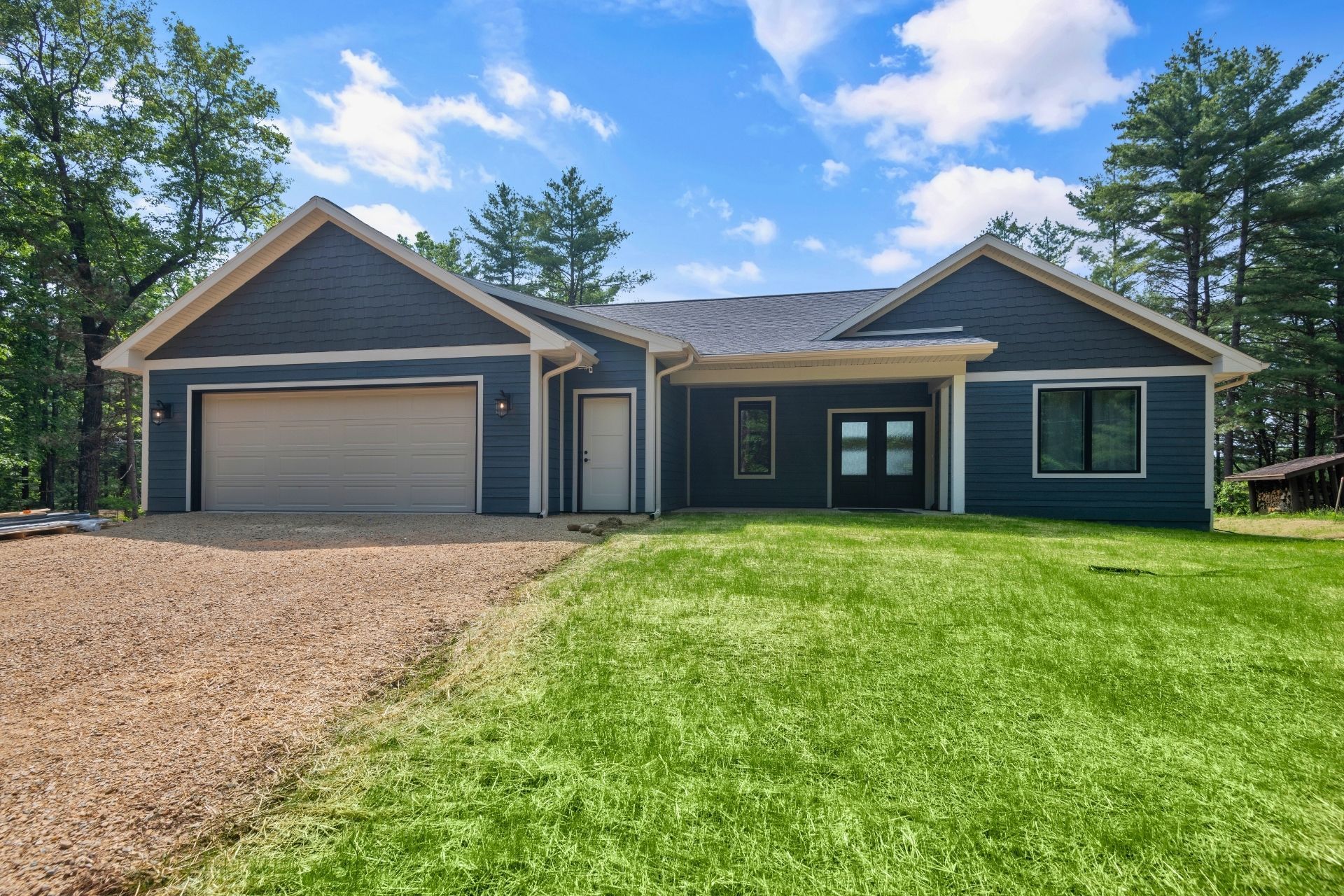 A blue house with a garage and a lot of grass in front of it.