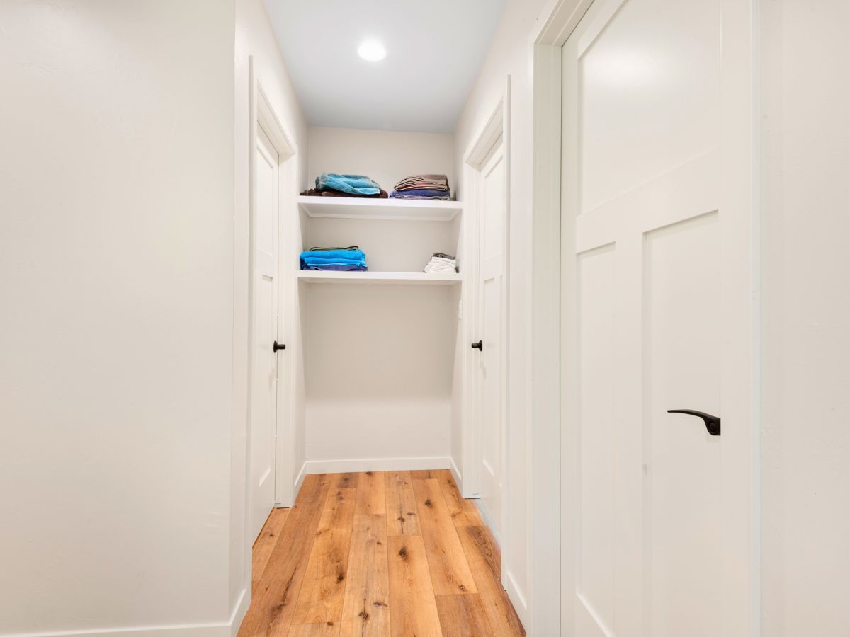 A hallway with wooden floors and shelves in a house.
