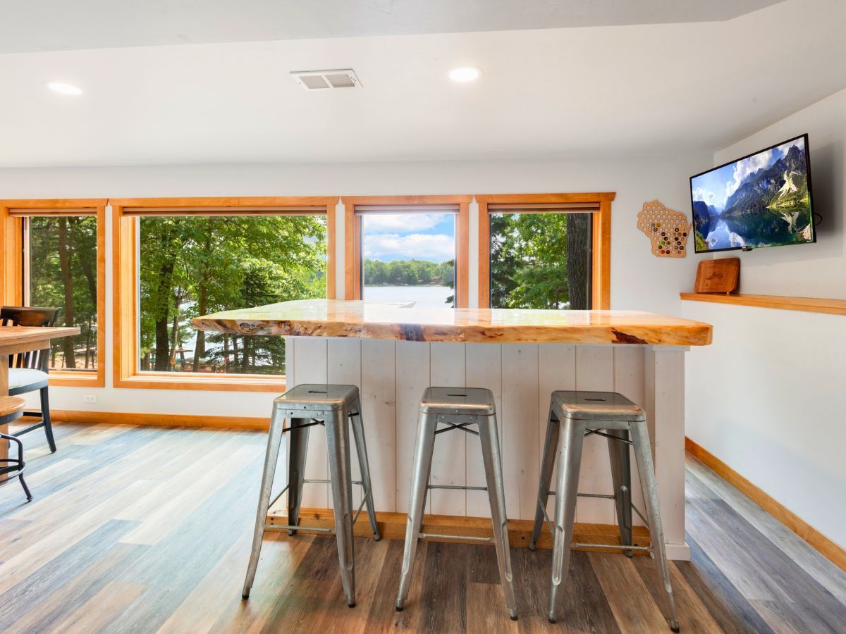 A kitchen with a large island and stools and a flat screen tv on the wall.