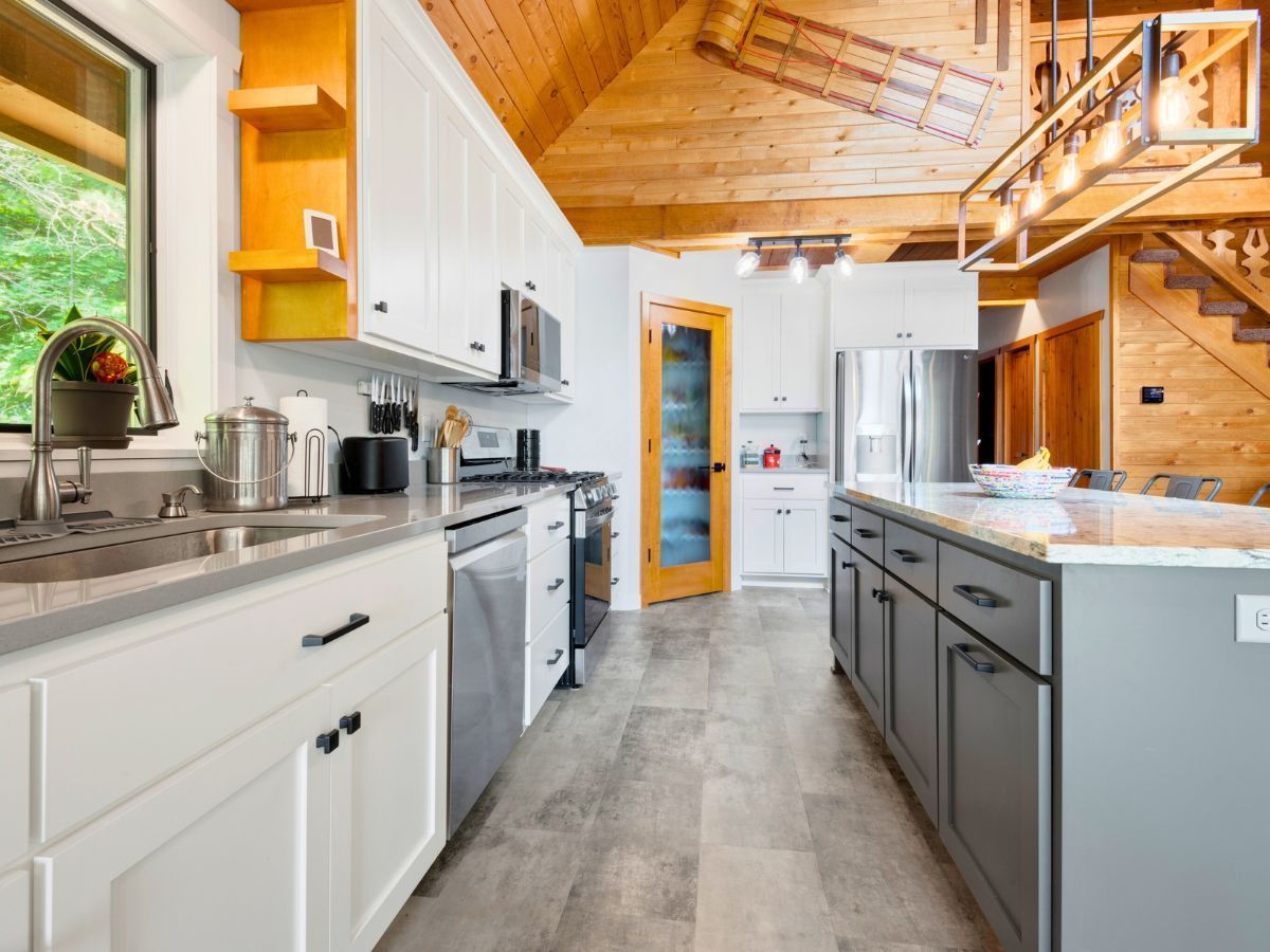 A kitchen with white cabinets , stainless steel appliances , and a large island.