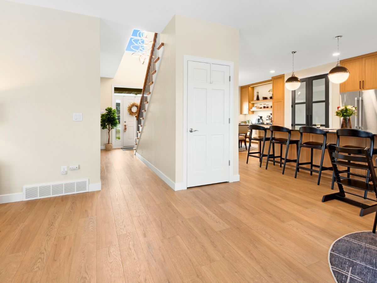 A living room with hardwood floors and a staircase leading to the kitchen.