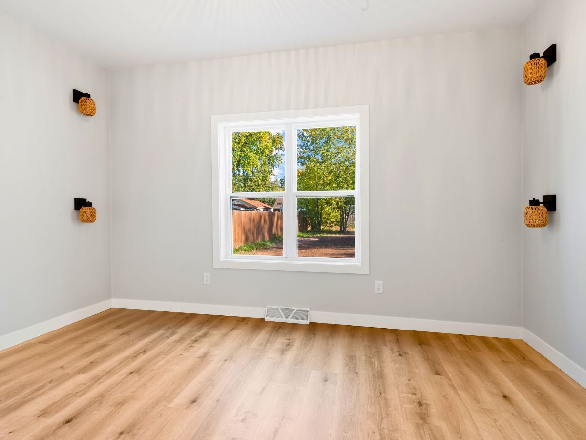 An empty room with hardwood floors and a window.