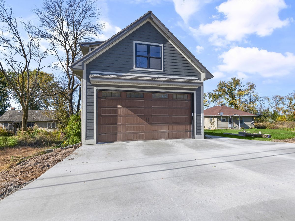 A garage with a concrete driveway in front of it.