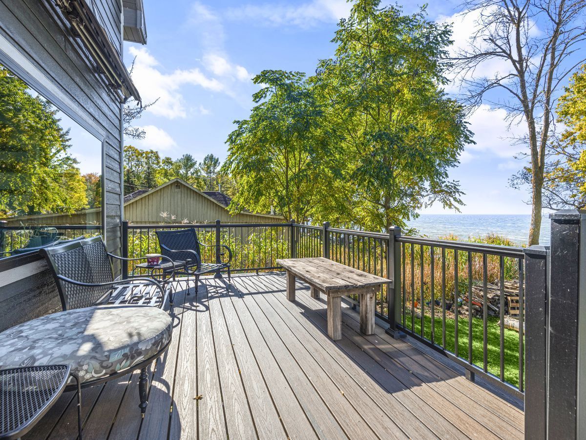 A large wooden deck with a bench and chairs overlooking the ocean.