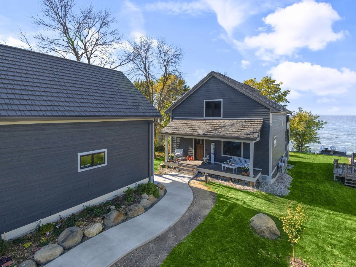 A house with a porch and a garage next to a body of water.