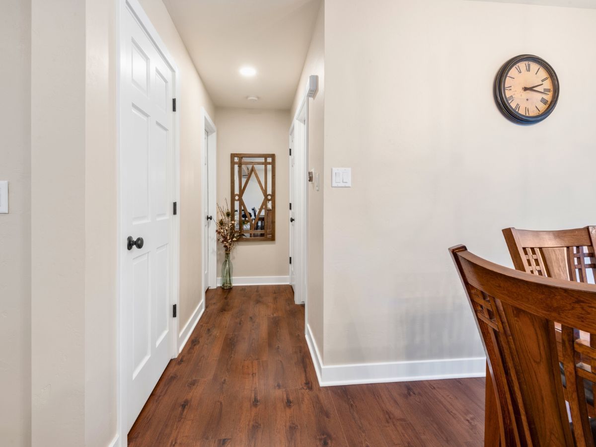 A hallway leading to a dining room with a clock on the wall.