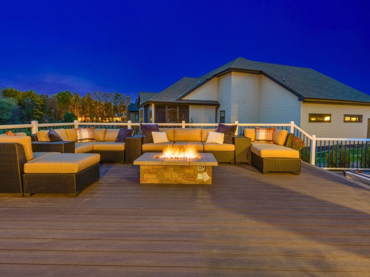 There is a fire pit on the deck with a lot of furniture on it.