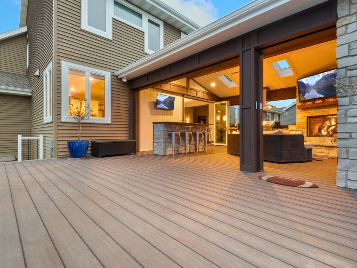 A large deck with a sliding glass door leading to a living room.