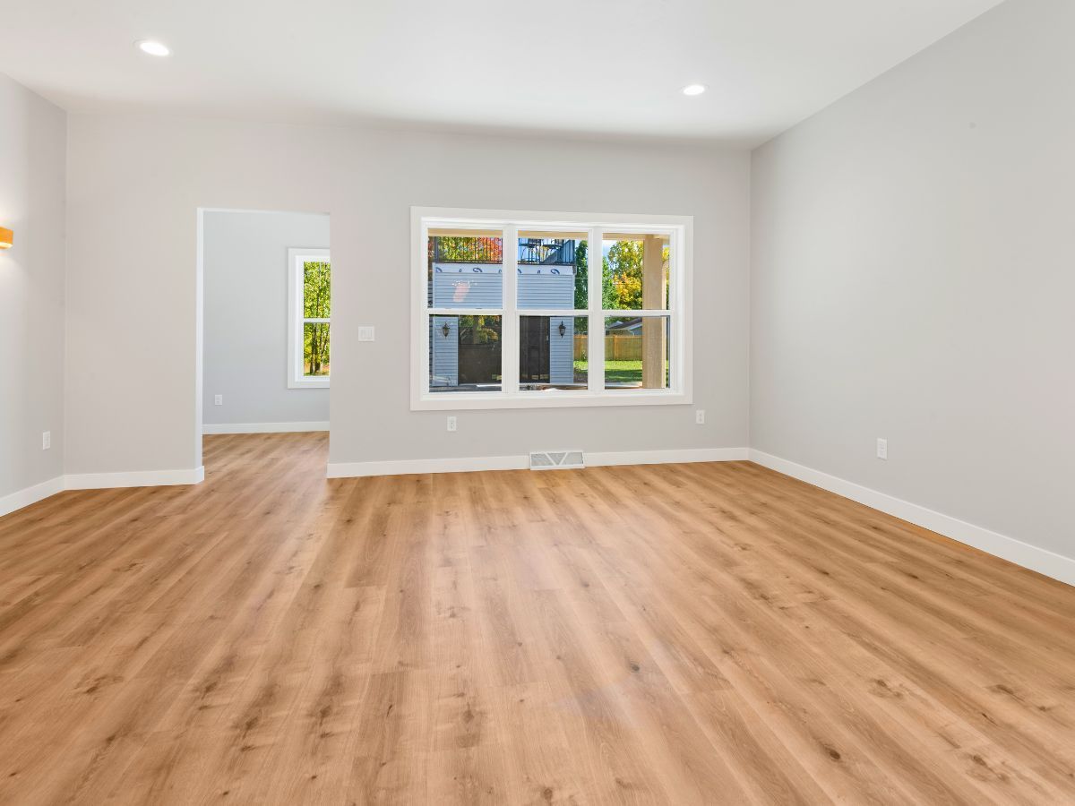 An empty living room with hardwood floors and a large window