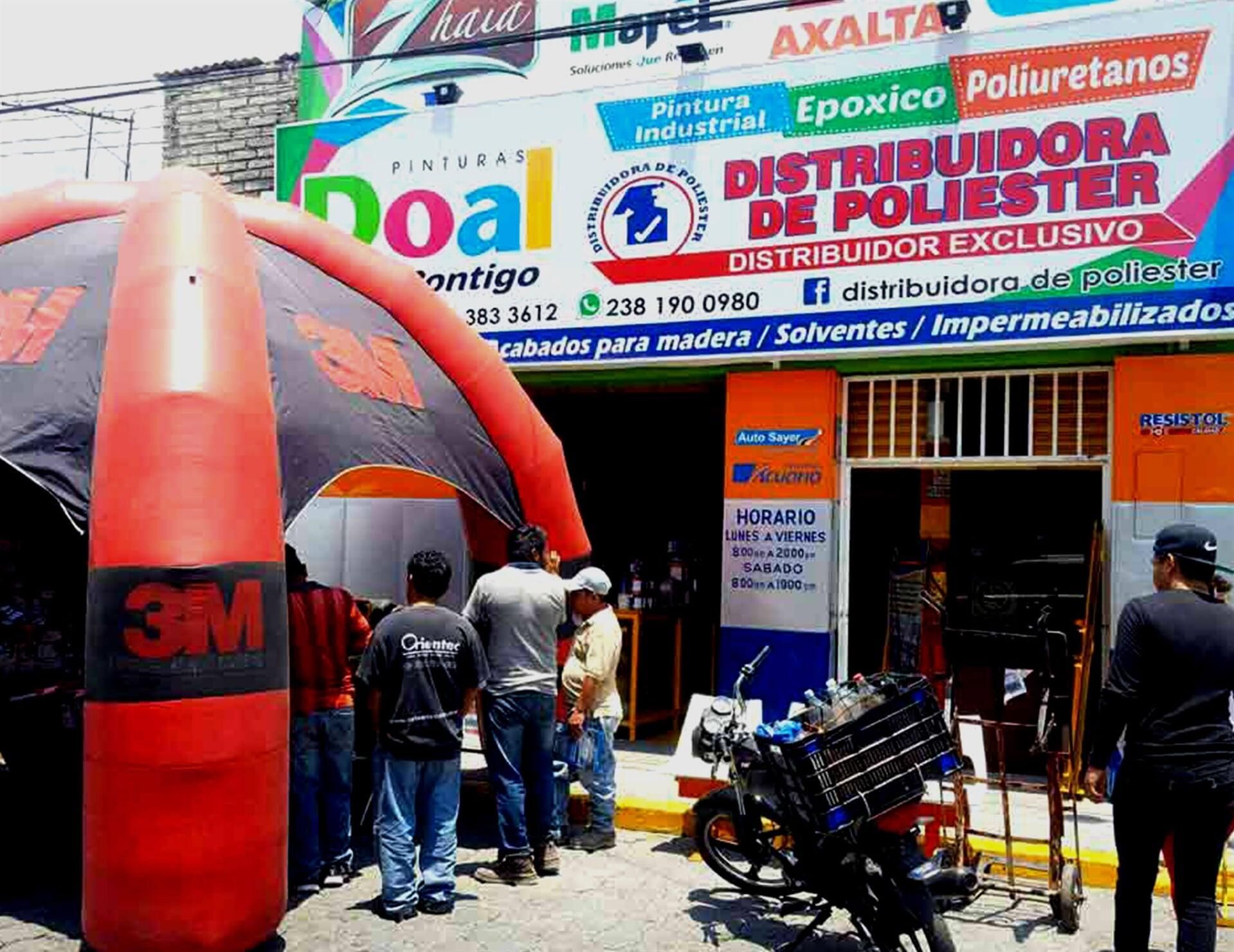 Un grupo de personas paradas afuera de una tienda llamada distribuidora de poliester