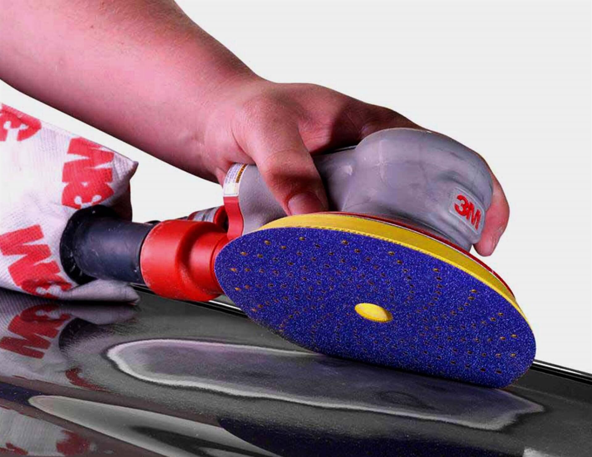 Una persona está lijando un coche con una lijadora 3M.