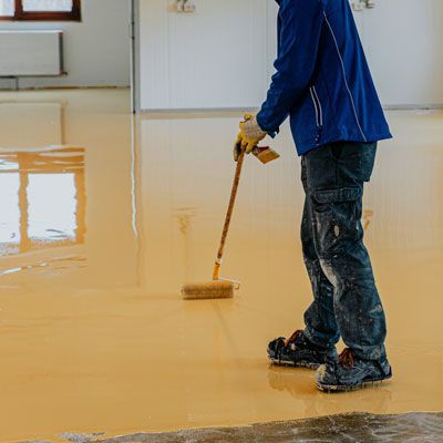 Un hombre está pintando un piso con un pincel.