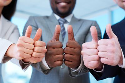 Business people in suits giving thumbs up in a meeting room