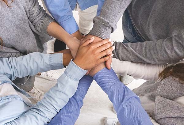 Hands stacked together in a circle, symbolizing teamwork and unity.