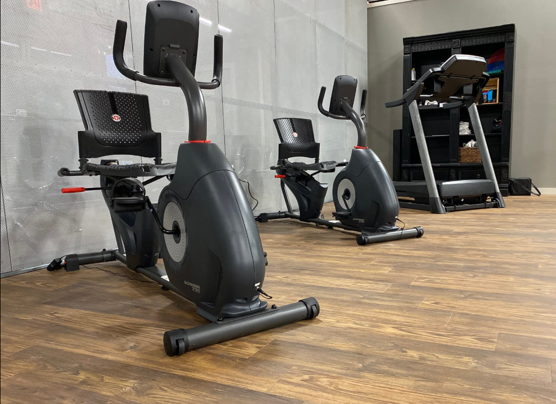 There are two exercise bikes and a treadmill in the room.