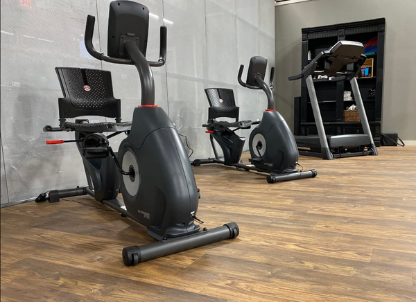 There are two exercise bikes and a treadmill in the room.