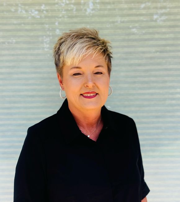 A woman wearing a black shirt and earrings is smiling for the camera.