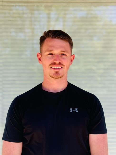 A man wearing a black under armour shirt is smiling for the camera.