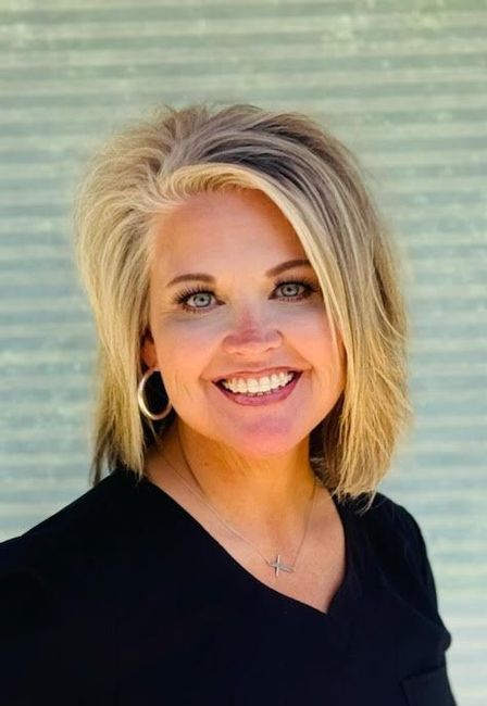A woman wearing a black shirt and earrings is smiling for the camera.