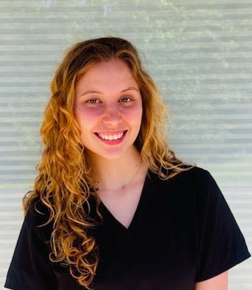 A woman in a black scrub top is smiling for the camera.