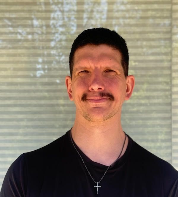 A man wearing a black shirt and a cross necklace