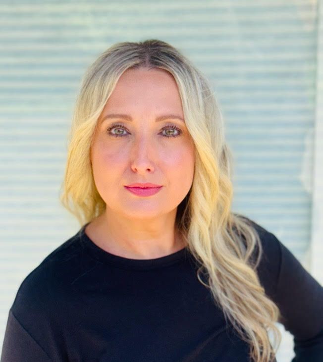 A woman with blonde hair is wearing a black shirt and posing for a picture.