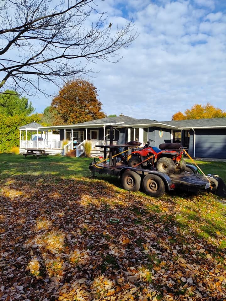 A trailer with a dune buggy on it is parked in front of a house.