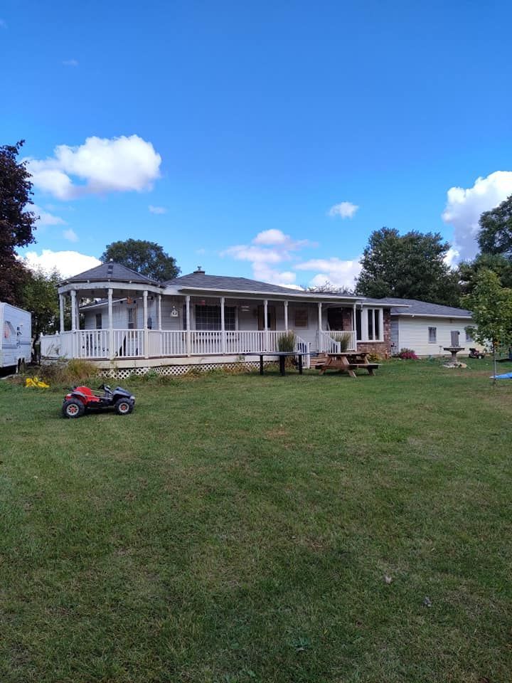 A house with a large porch and a lawn mower in front of it.