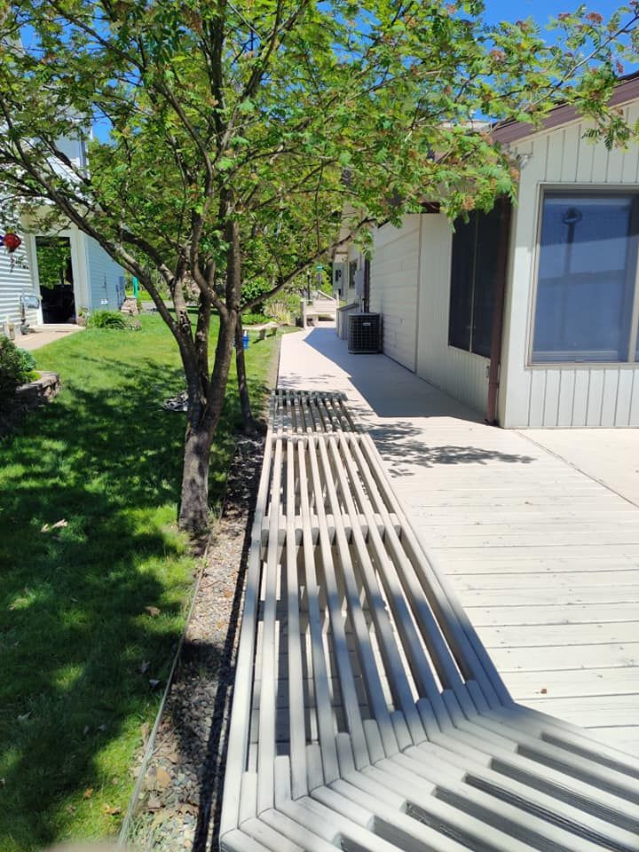 A wooden walkway leading to a house with trees in the background