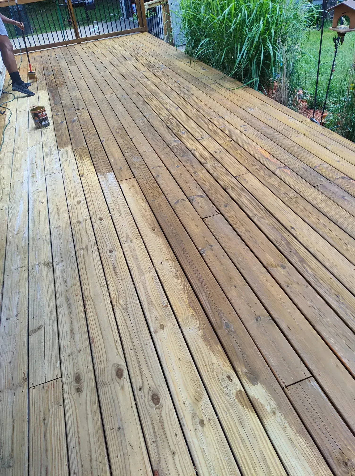 A person is painting a wooden deck with a brush.