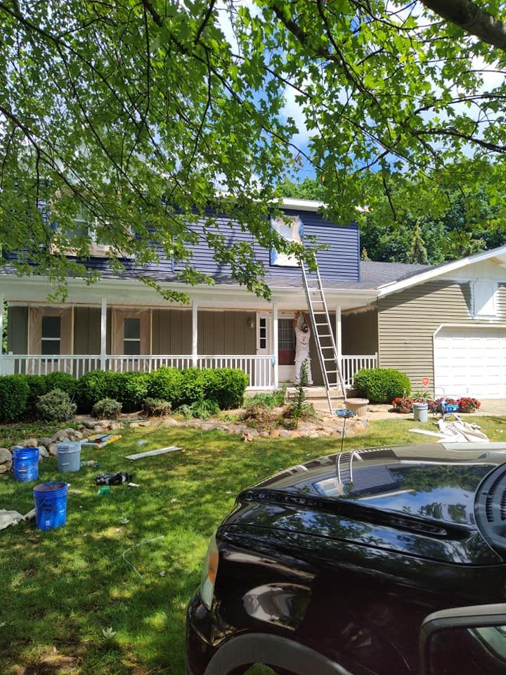 A black truck is parked in front of a house being painted.