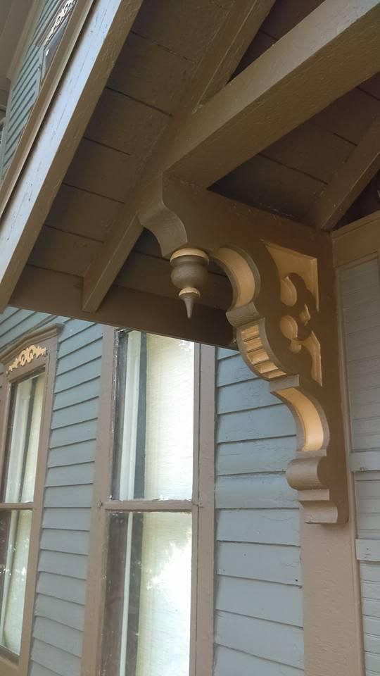 A close up of a wooden bracket on the side of a house