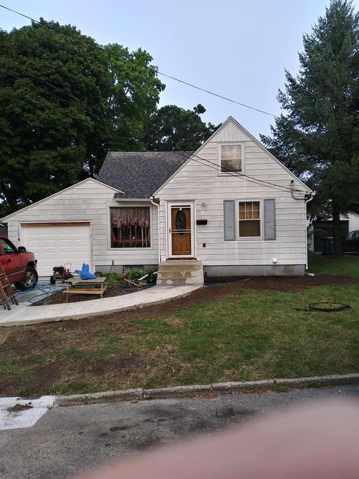 A white house with a red truck parked in front of it.