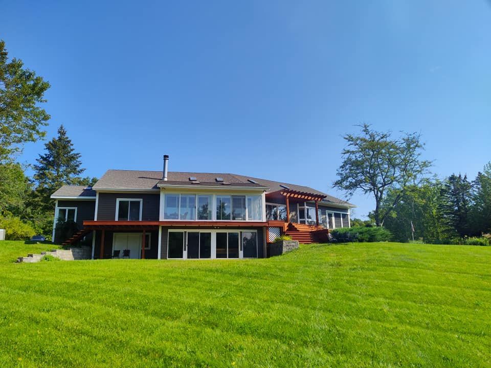 A large house with a lot of windows is sitting on top of a lush green field.