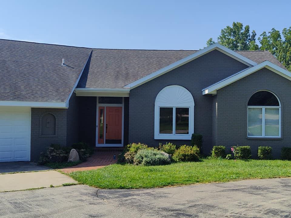 A gray house with a white garage door and a red door