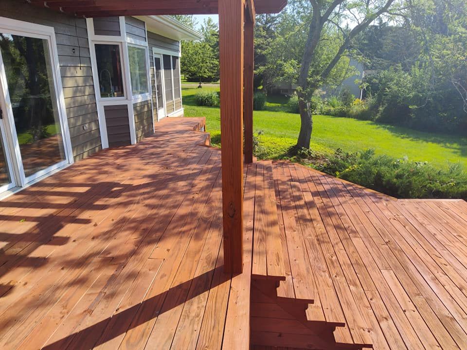A wooden deck with stairs leading up to it is in front of a house.