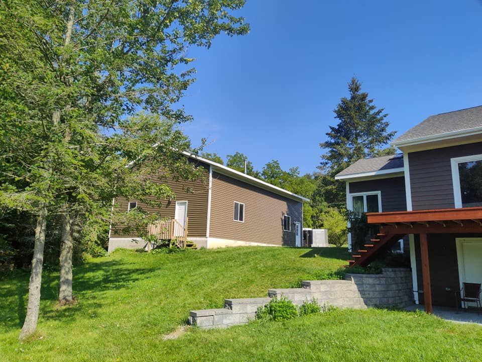 Two houses are sitting next to each other on a lush green hillside.