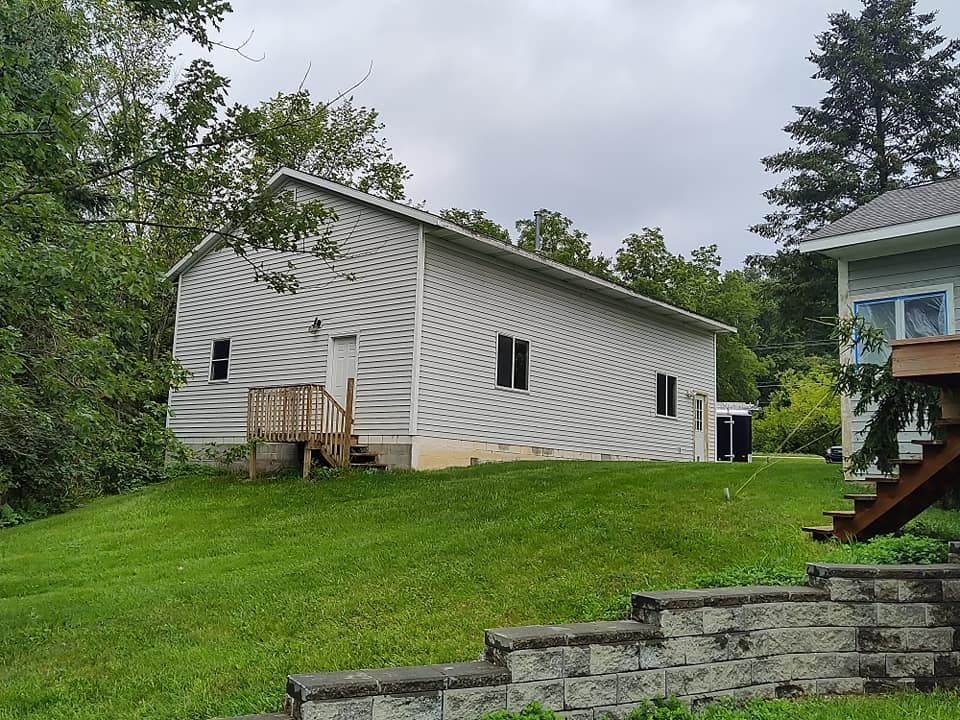 A white house is sitting on top of a lush green hill.