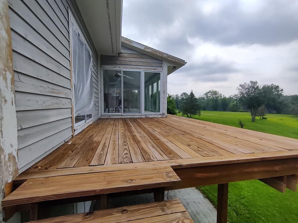 A wooden deck is sitting in front of a house.