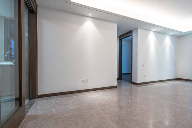 An empty living room with white walls and a tiled floor.