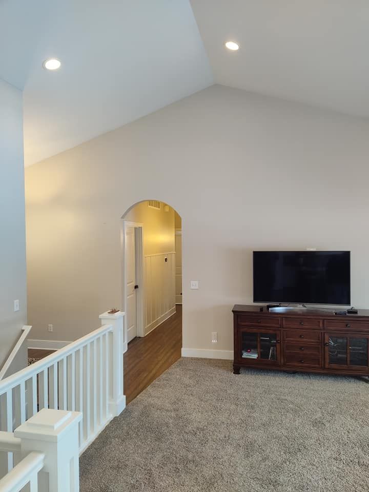 A living room with a vaulted ceiling and a flat screen tv.