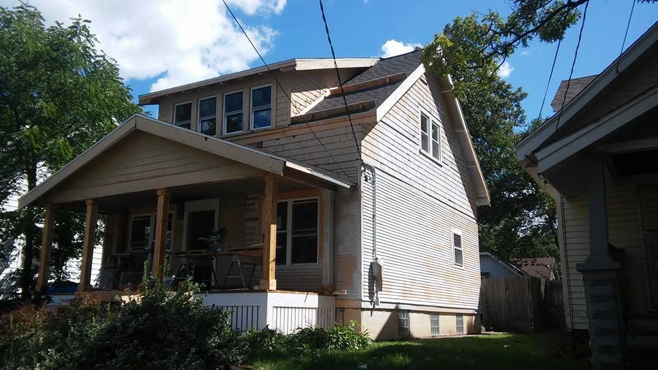 A white house with a porch and a blue sky in the background